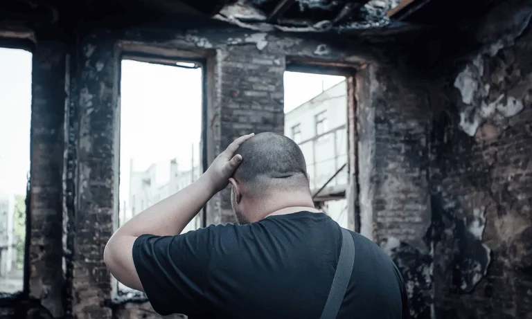 Homeowner standing inside fire damaged house in Florida assessing structural damage